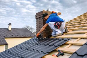 A homeowner using a soft brush to remove moss from a shingled roof on a partly cloudy day.